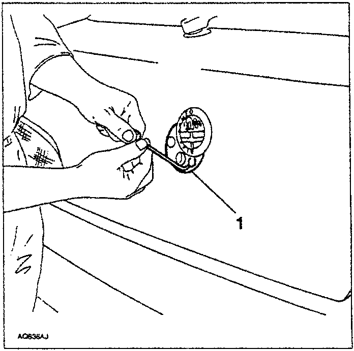 Hand using a punch to slacken a screw on the tailgate lock unit.