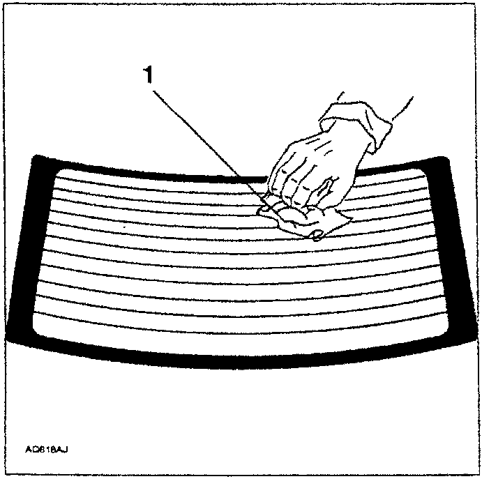 Hand applying a cleaning agent to the surface of a rear screen glass panel.