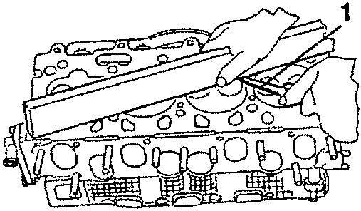 Illustration showing a hand using a flat surface to check the flatness of a cylinder head.