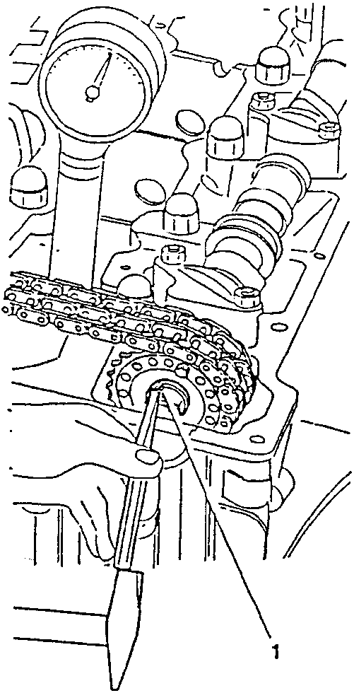 Diagram showing a hand using a tool to raise the edge of a nut retainer near a toothed wheel and chain.