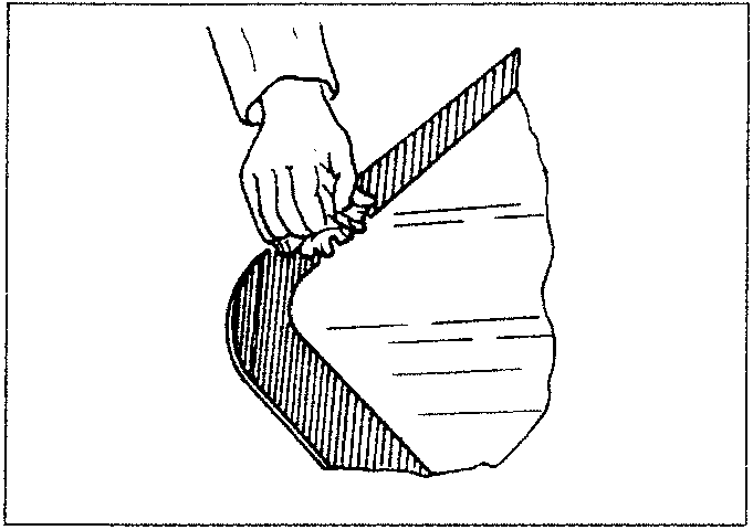 Hand applying a cleaning cloth to the edge of a windshield.