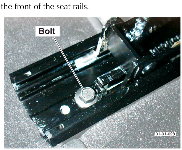 Close-up photograph of a bolt securing the front seat rail to the vehicle floor pan.
