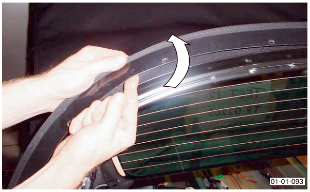 A pair of hands lifting the edge of the black roof material away from the tension bow.