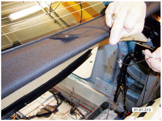 A hand pulling the roof material back to expose the tension cord mounts inside the vehicle structure.