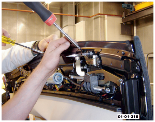 A person using a screwdriver to remove screws securing the roof material to the header rail.
