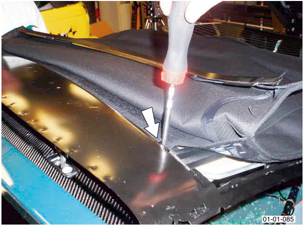 A screwdriver being used on the roof lining near the header rail.