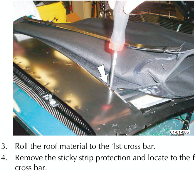 A screwdriver securing the roof material to the frame cross bar.