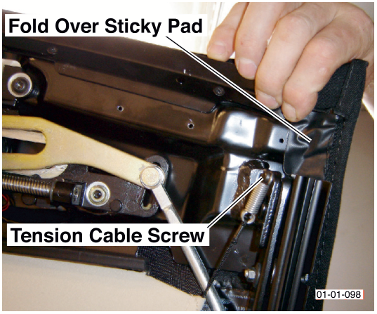 A hand folding a sticky pad over a metal component near a tension cable screw. Labels read Fold Over Sticky Pad and Tension Cable Screw.