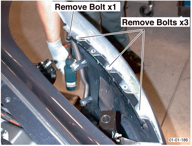 Photograph showing a hand removing a bolt from the underside of the vehicle near the bumper, with callouts 'Remove Bolt x1' and 'Remove Bolts x3', figure number 01-01-186
