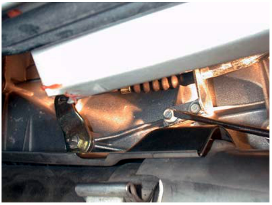 Close-up view of manual override cable connection point near exhaust component