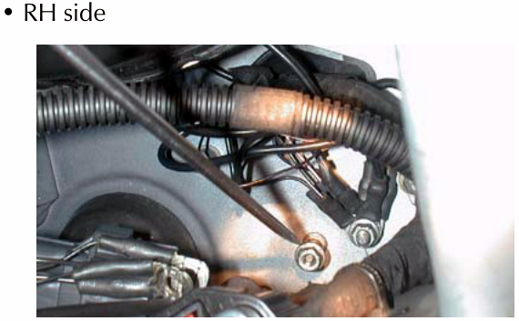 A view of the RH side of the engine bay showing various hoses, wiring looms, and mechanical components near the firewall.