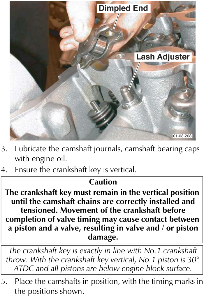 A close-up photograph showing a hand installing a camshaft follower onto a lash adjuster. Labels point to the 'Dimpled End' of the follower and the 'Lash Adjuster' below it. The part number 01-03-208 is visible in the bottom right corner.