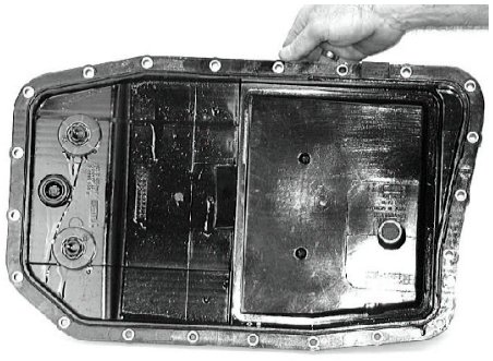 A hand pressing an O-ring seal into the transmission oil filter housing