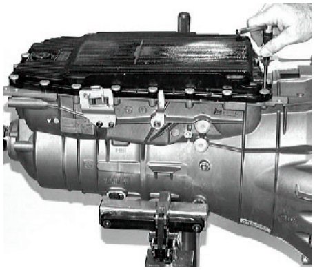 A hand tightening a screw on the transmission sump