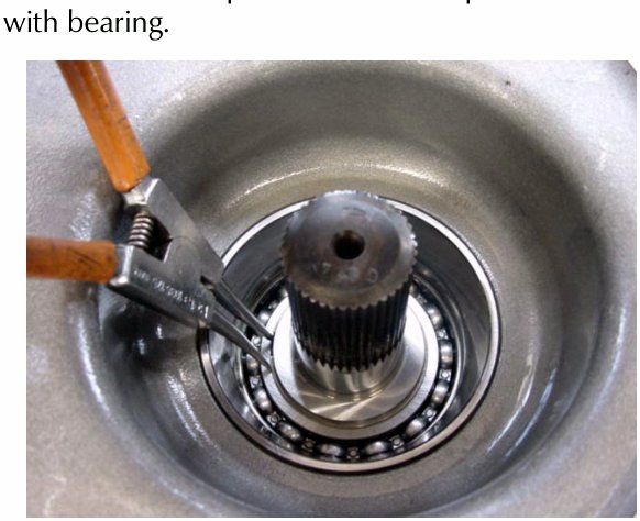 Close-up photo of a circlip being removed from an output shaft bearing using pliers