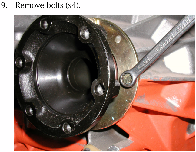 A spanner being used to remove bolts from the output shaft cover of a differential housing.