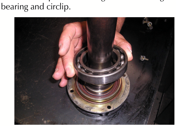 A hand pressing a bearing onto an output shaft that is seated in a seal casing.