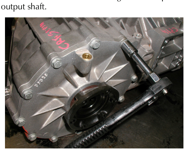 A slide hammer tool attached to the bolts on the side of a silver differential housing, used to pull off the cover.