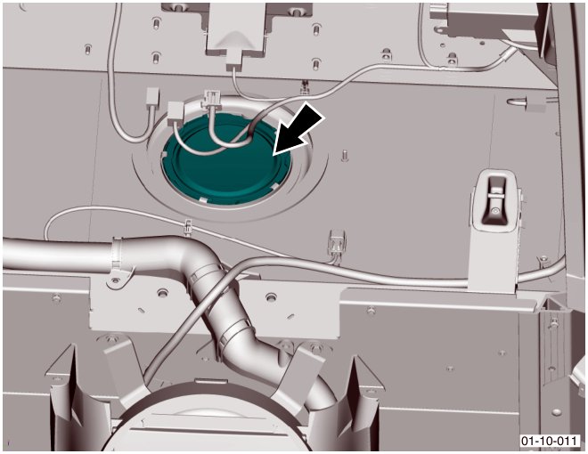 View of the fuel tank flange area showing the circular service cover and surrounding components within the vehicle cabin floor.