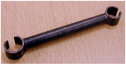 A dark metal open-ended wrench lying on a wooden surface.