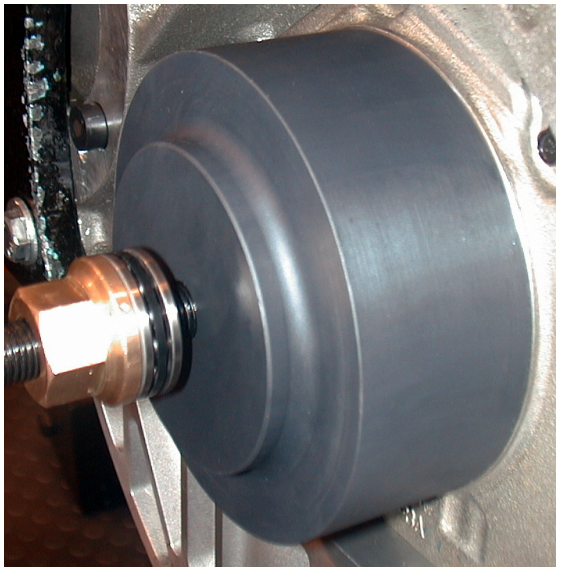 A close-up view of the oil seal install tool fully seated against the engine housing with the nut and bolt assembly visible.