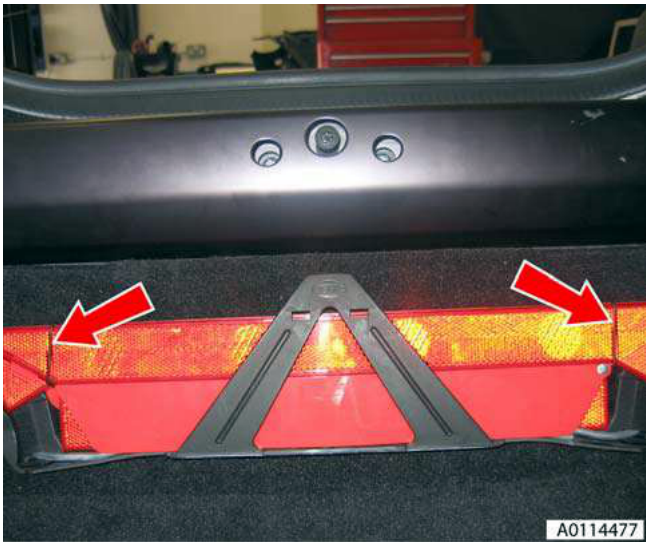 Warning triangle mounted inside the boot, with red arrows pointing to its mounting clips.