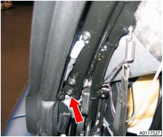 Close-up view showing a hand using a tool to remove a screw from a seal retaining bracket on the rear seal assembly