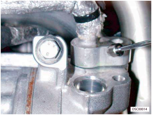 Close-up of compressor pipes with bolts being removed