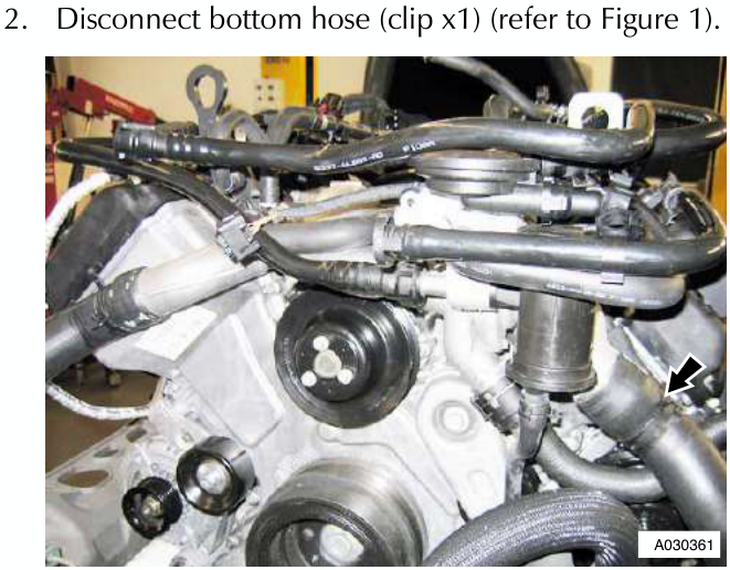 Engine bay showing coolant hoses and components with an arrow pointing to a connection point on the right side of the manifold area.