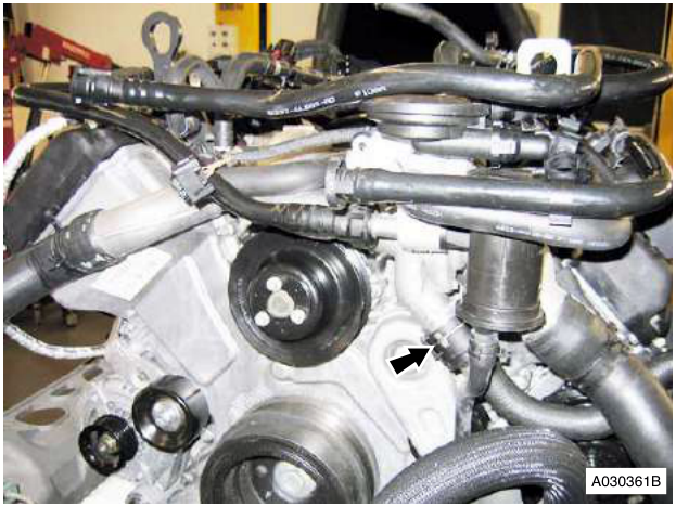 Engine bay showing hoses and components with an arrow pointing to a connection point on the right side