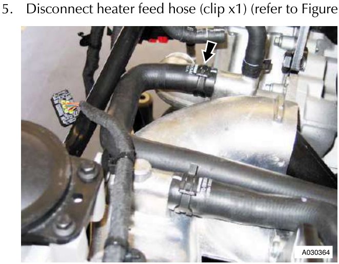 Close-up of black rubber hoses connected to a metal component with an arrow pointing to a clip securing a hose