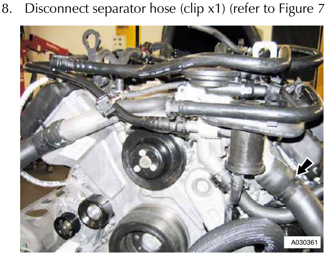 Engine assembly showing various hoses and wiring, with an arrow pointing to a hose secured by a clip near the bottom right