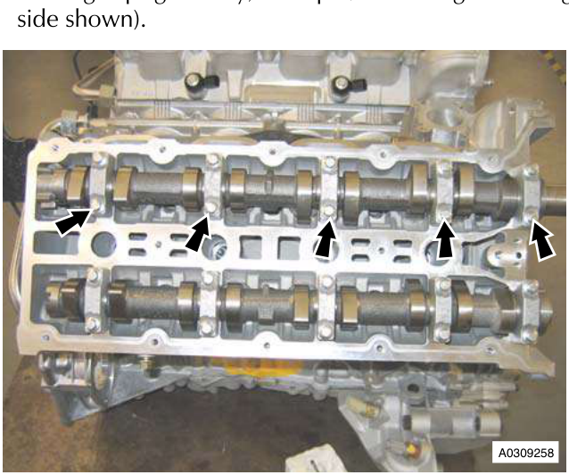 Engine head with camshafts and bolts, arrows pointing to bolts