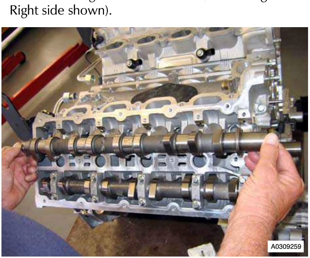 Hand removing camshaft from engine head