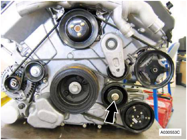 Engine with belt and pulleys, arrow pointing to a bolt