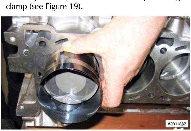 Hand installing a piston ring clamp into a cylinder bore