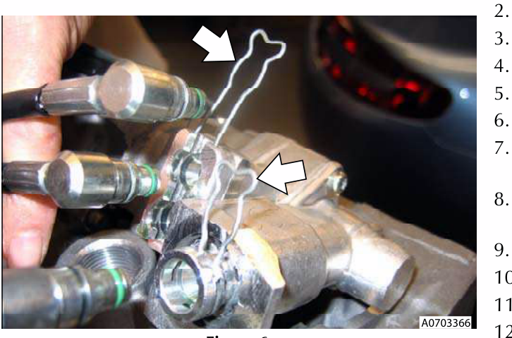 Hand removing clips from hoses connected to a transmission shifter unit.