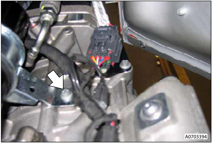 Close-up of the valve block and transaxle connection area, showing bolts and hoses.