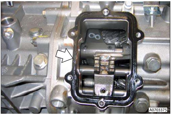 Close-up of transmission housing with arrow pointing to gasket area, part number A0703375 visible