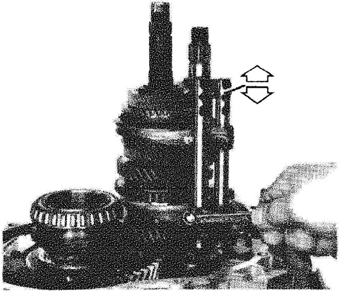 A hand moving a control rod up and down on the gearbox assembly, indicated by double-headed arrows.