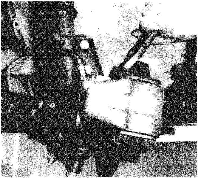 Close-up view of a hand using a tool to remove or fit a cotter pin on the brake caliper assembly