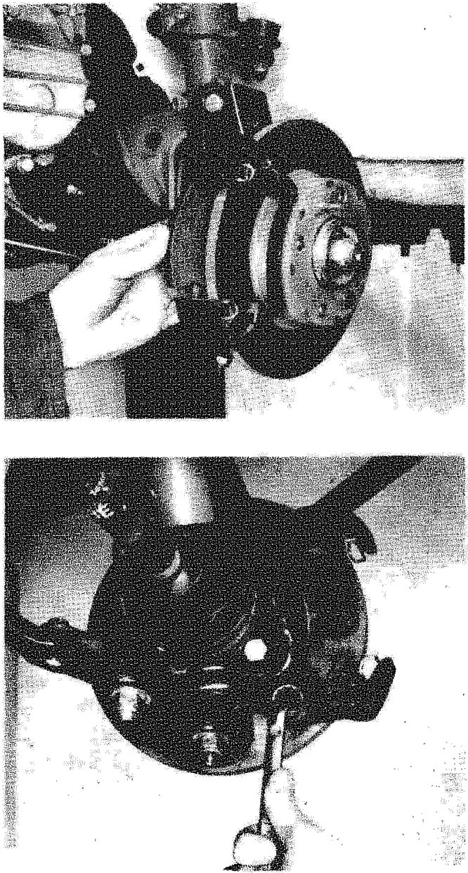 A hand removing the brake caliper from the disc, exposing the brake pads inside the support bracket.