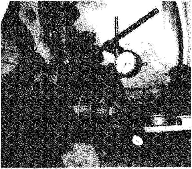 A photograph showing a hand using a measuring tool to check the thickness of a brake disc