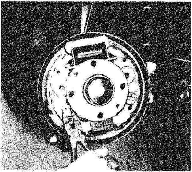 Rear brake assembly with a hand removing the shoe retaining pin