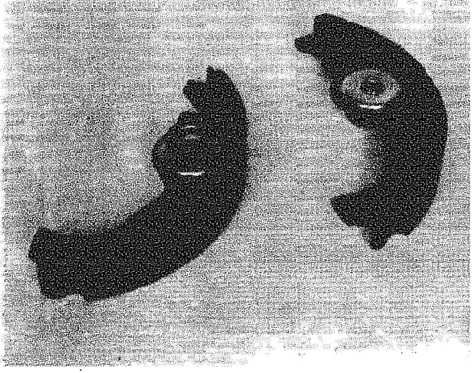Two curved brake shoes with friction material lining, lying on a flat surface.