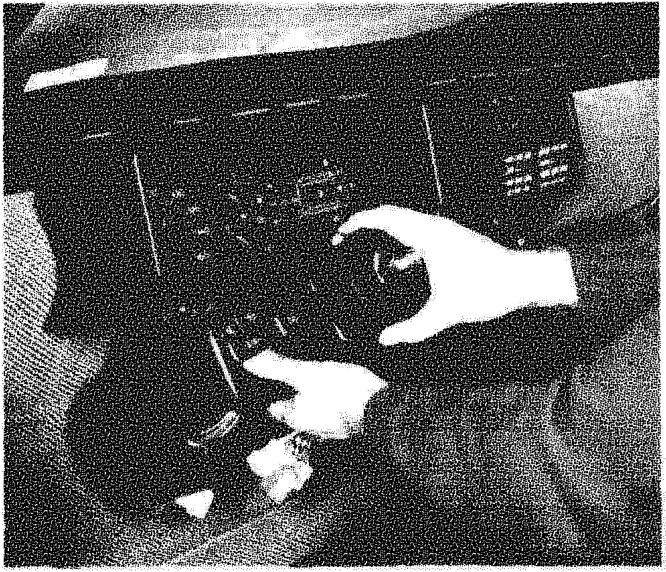 A hand removing the upper shield from the steering column area