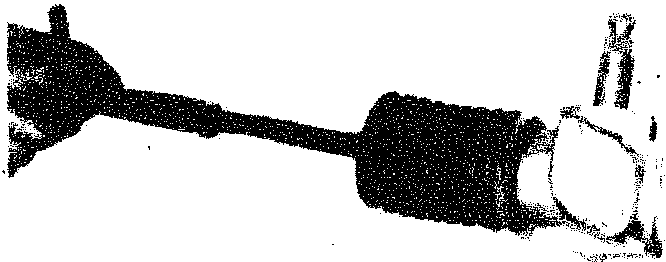 A hand holding a steering track rod assembly with a protective boot and ball joint end.
