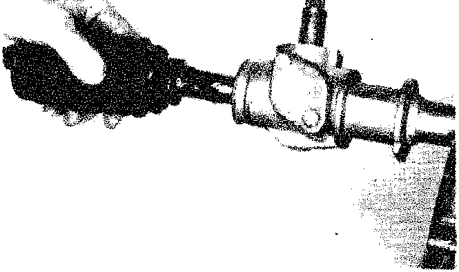 A close-up view of a hand manipulating the protective rubber boot on a steering track rod near the ball joint.