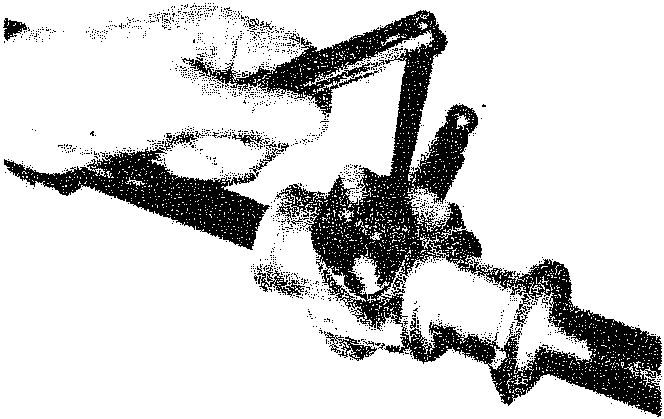 Photograph of a hand using a wrench to adjust a component on the steering rack.