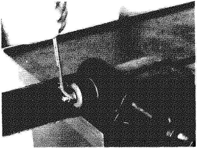 A reaction rod being worked on under the vehicle chassis with a tool inserted into the mounting